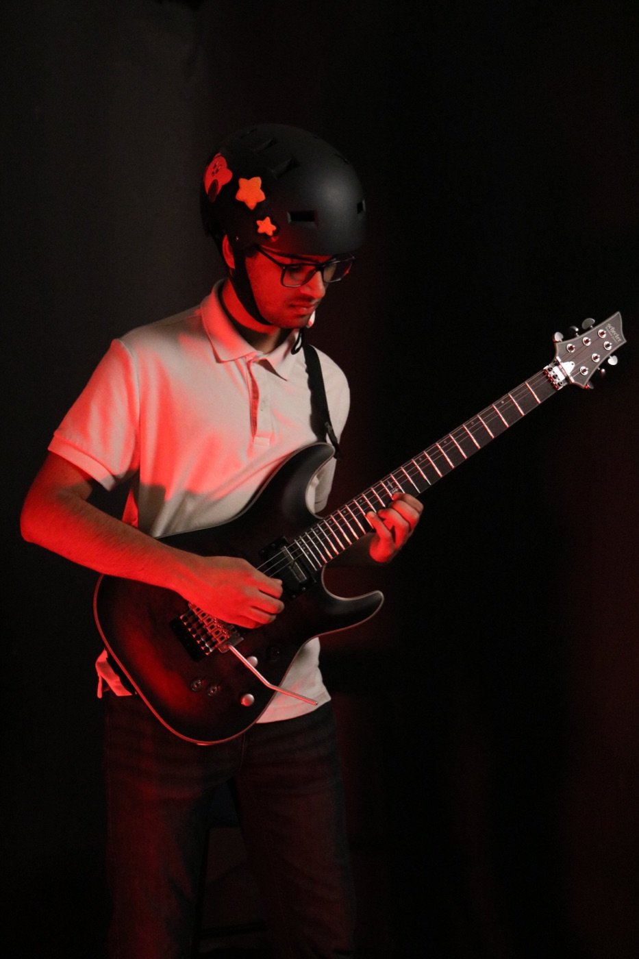 R.C. Napkin playing a black electric guitar under red stage lighting